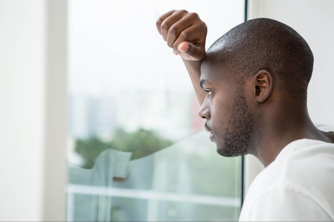 addict looking out of window with hand on head