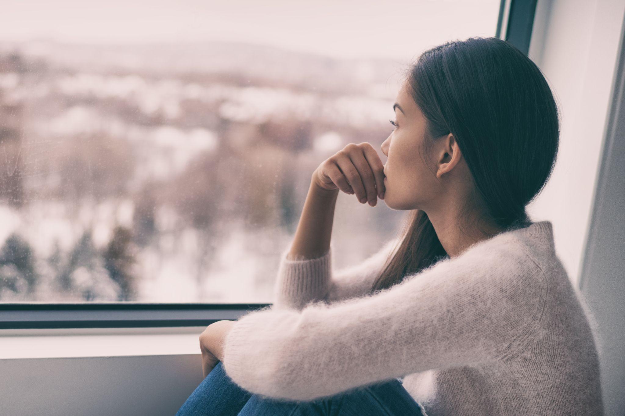 seasonal affective disorder mental health woman sad comtemplative looking out the window alone.