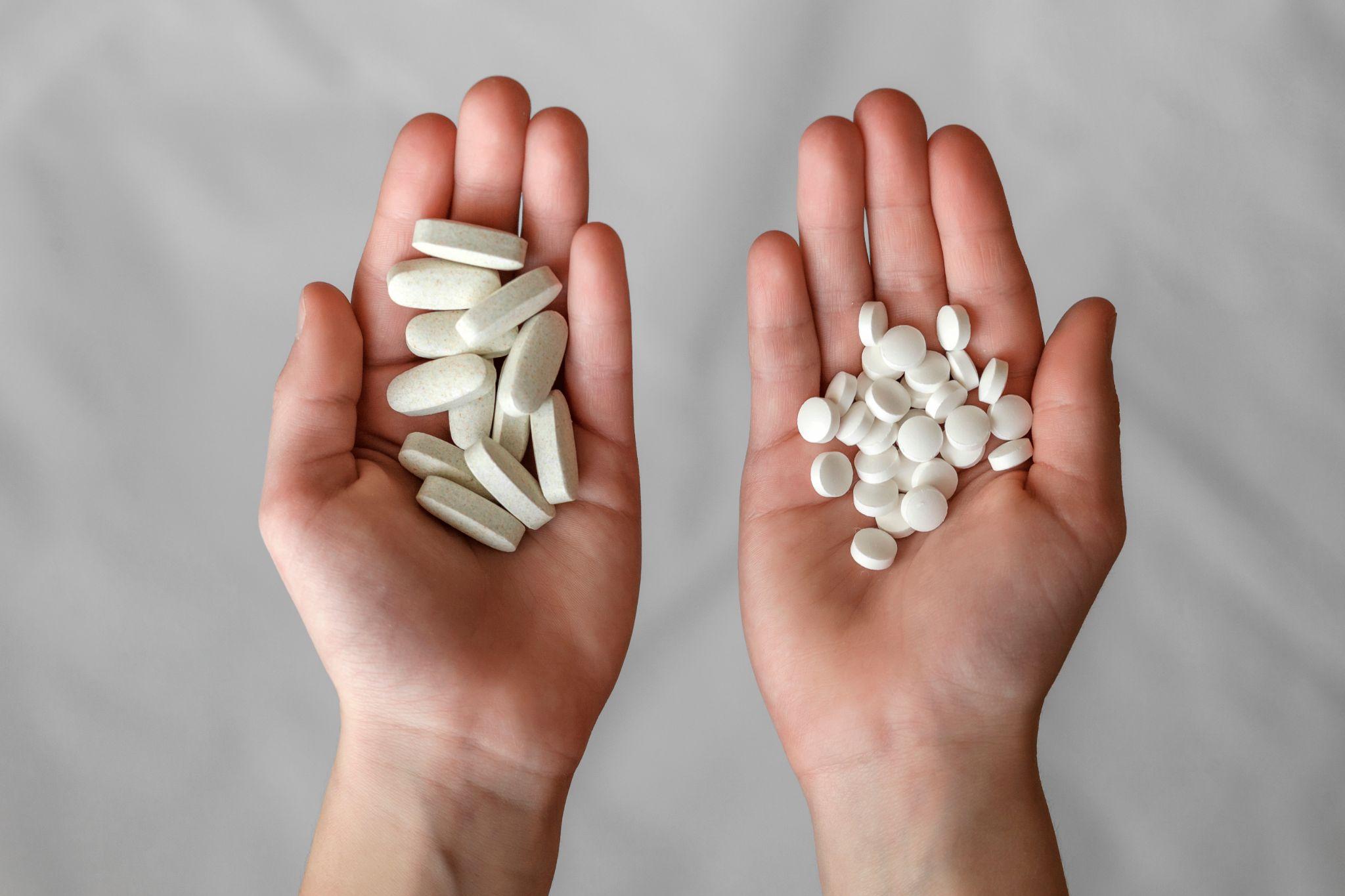 Pills in hands. Two handfuls of different pills on a gray background.