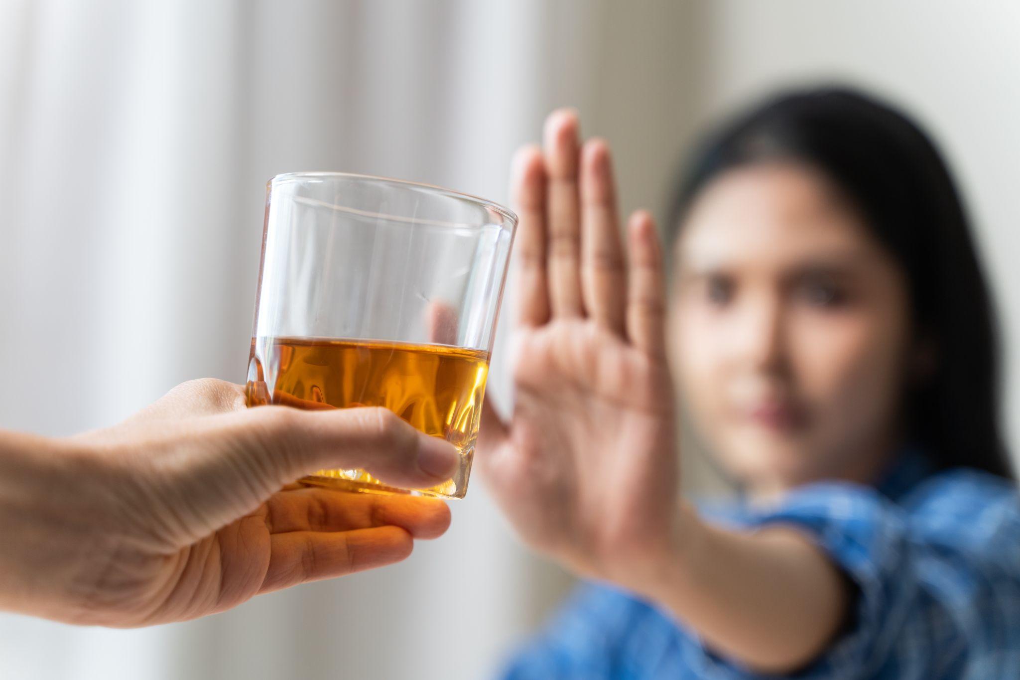 woman refusing to drink whiskey indoors