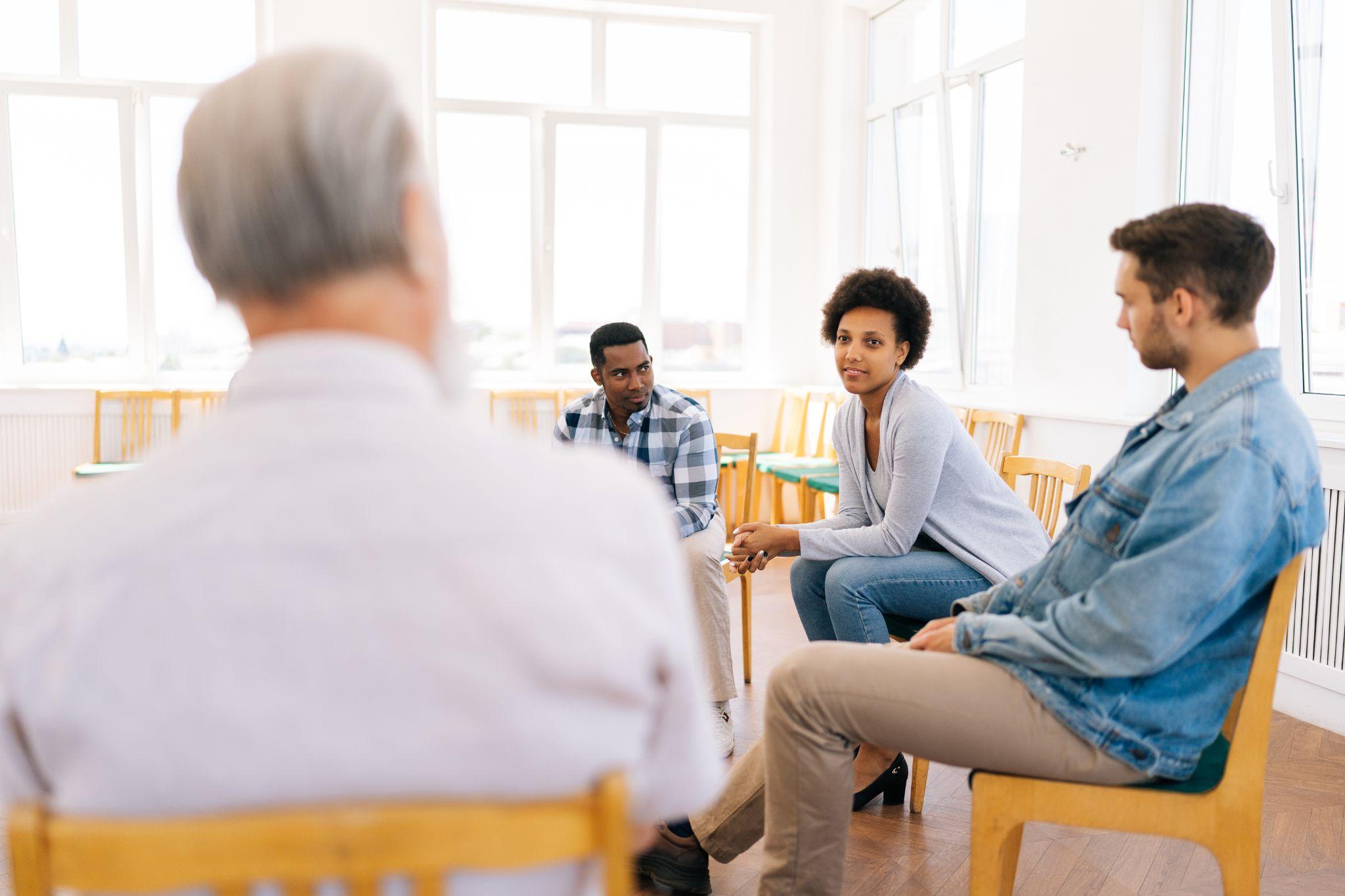 young woman sharing addiction story with group of people at alcohol anonymous therapy meeting. 