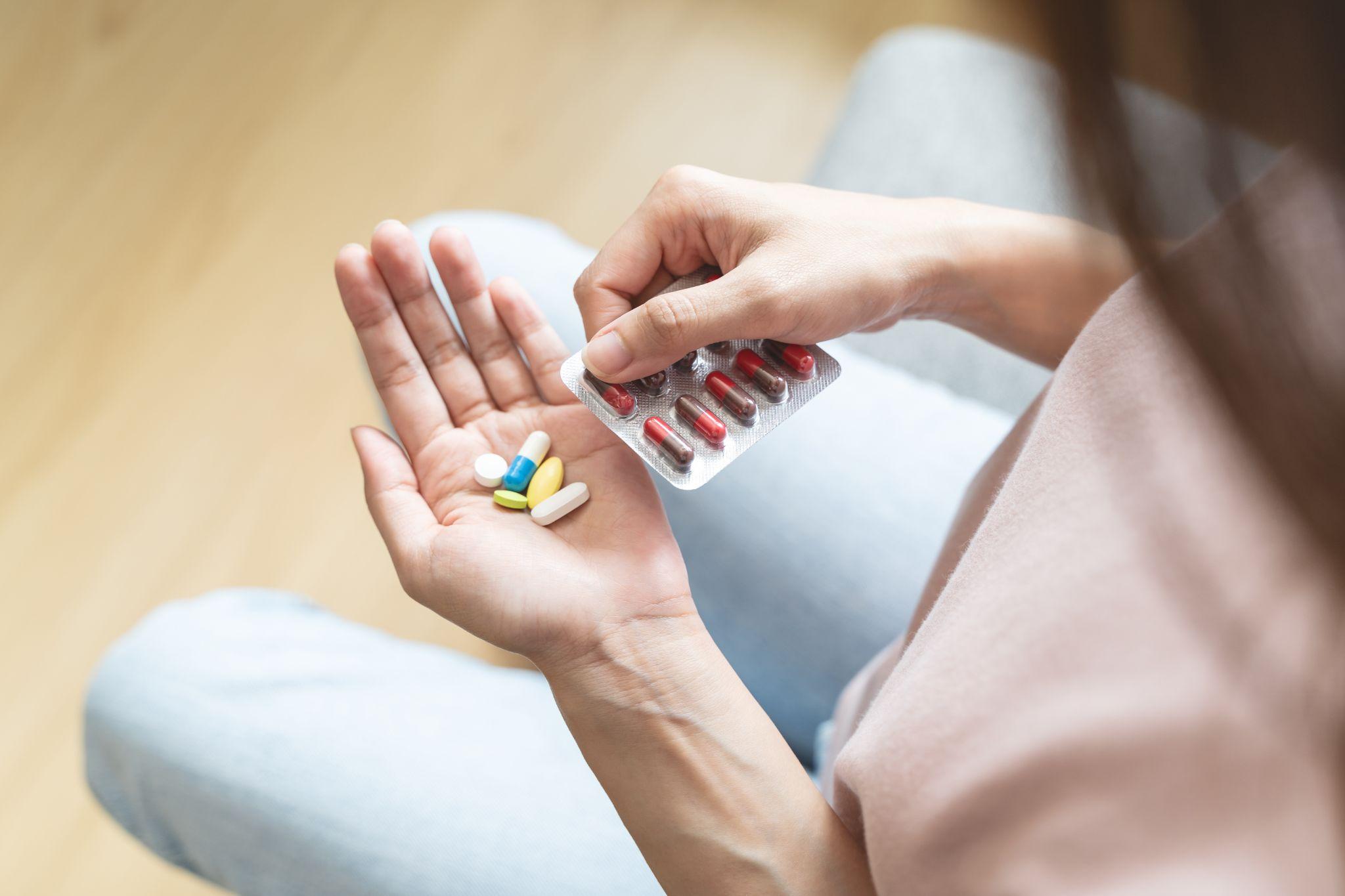 Close-up hands holding medication and water glass