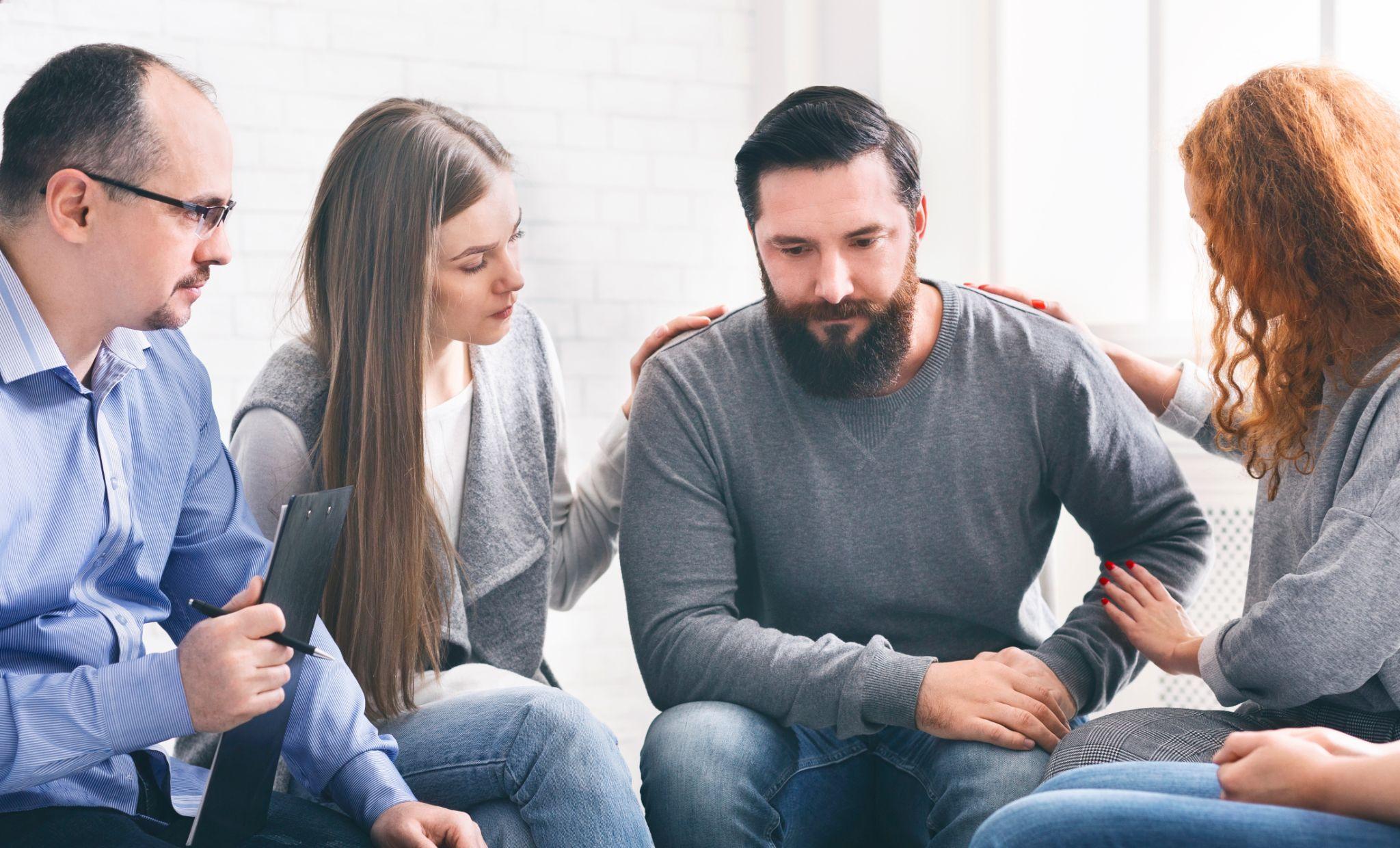 Group supporting depressed man with alcoholism problem