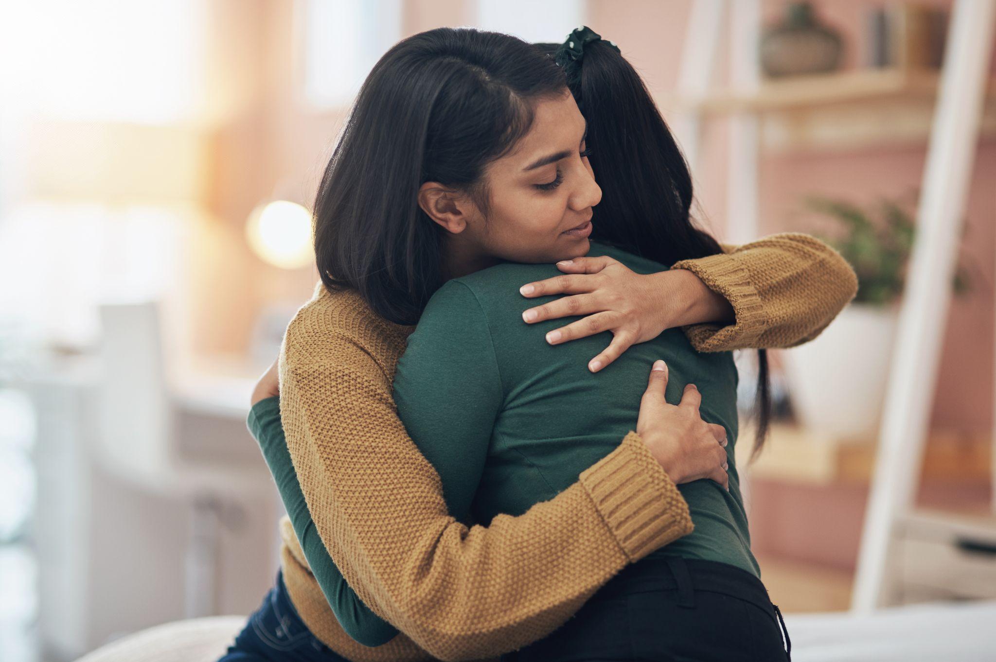 two young women embracing each other at home.