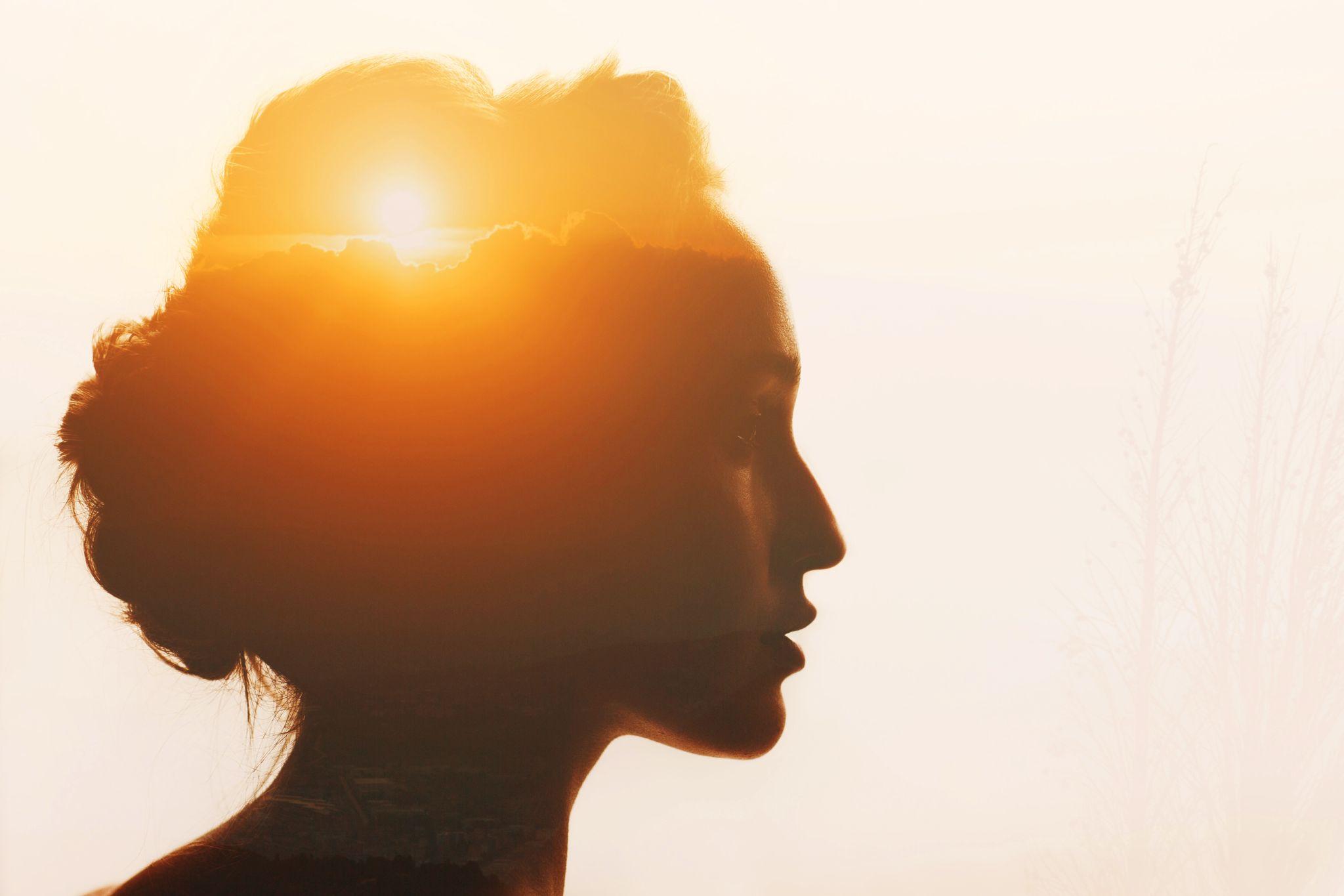 Woman with sunset and clouds beyond her head.