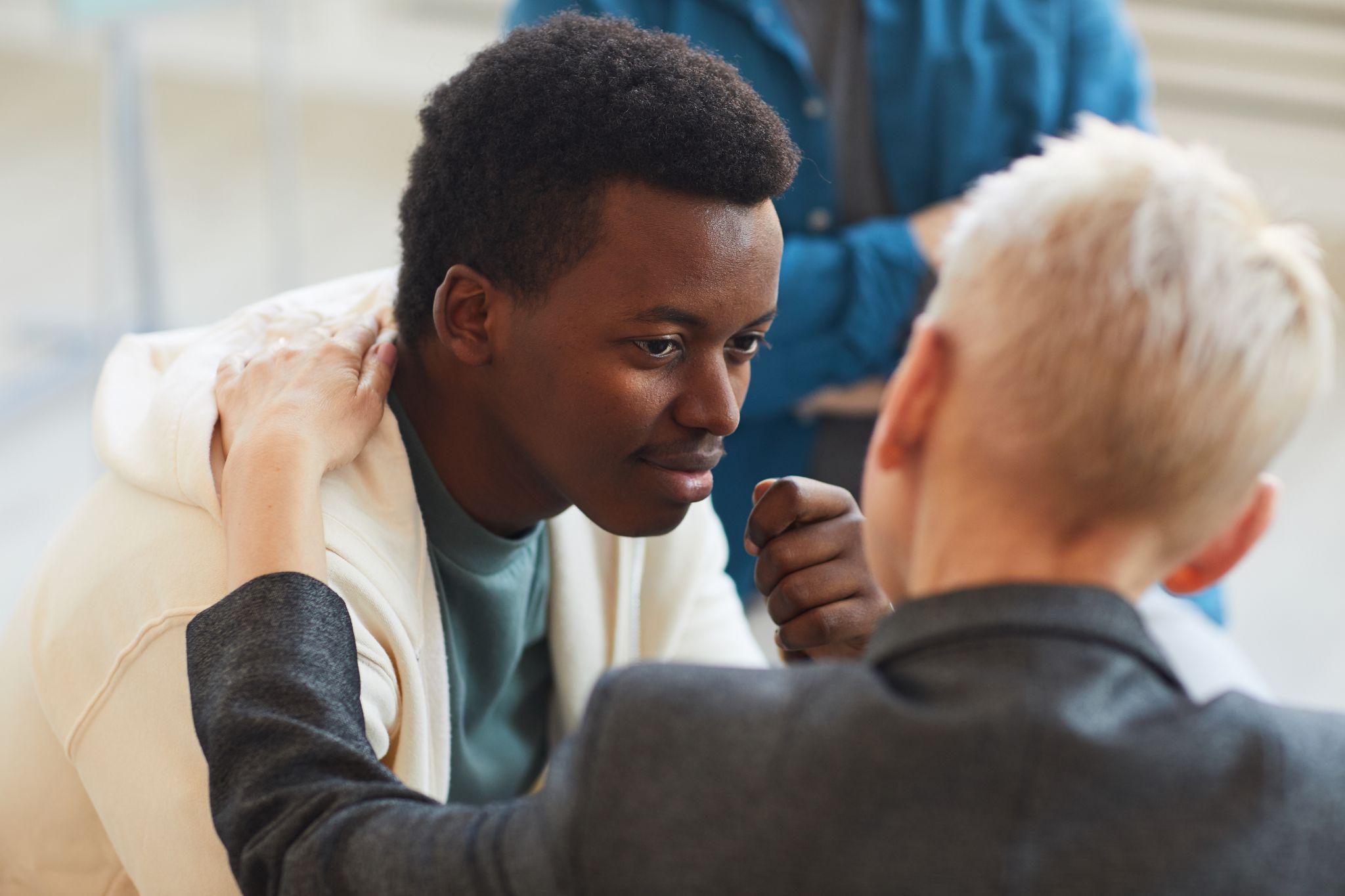 young African-American man smiling gratefully to psychologist while in support group circle