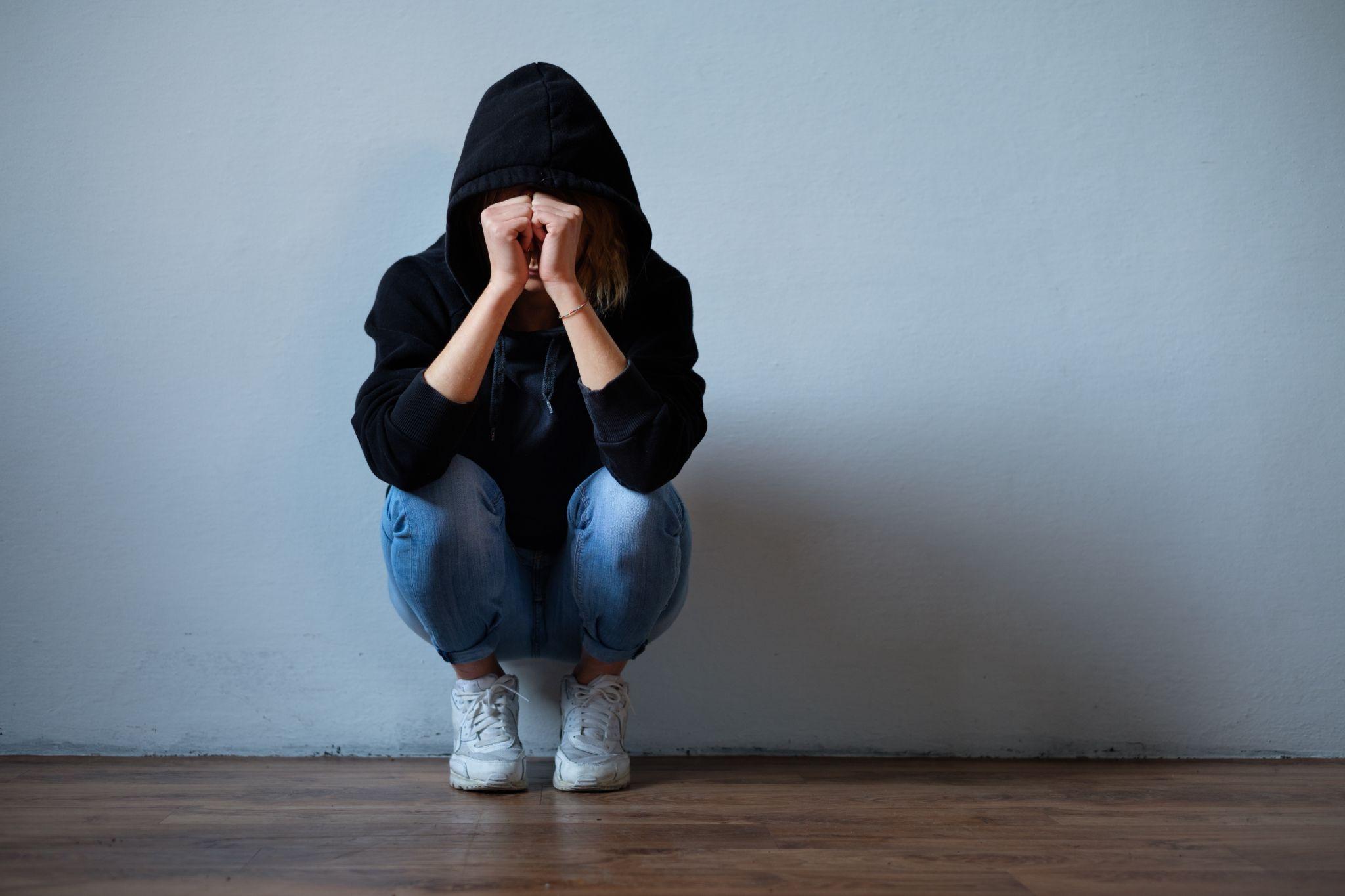 Young girl hiding her face under hooded sweatshirt