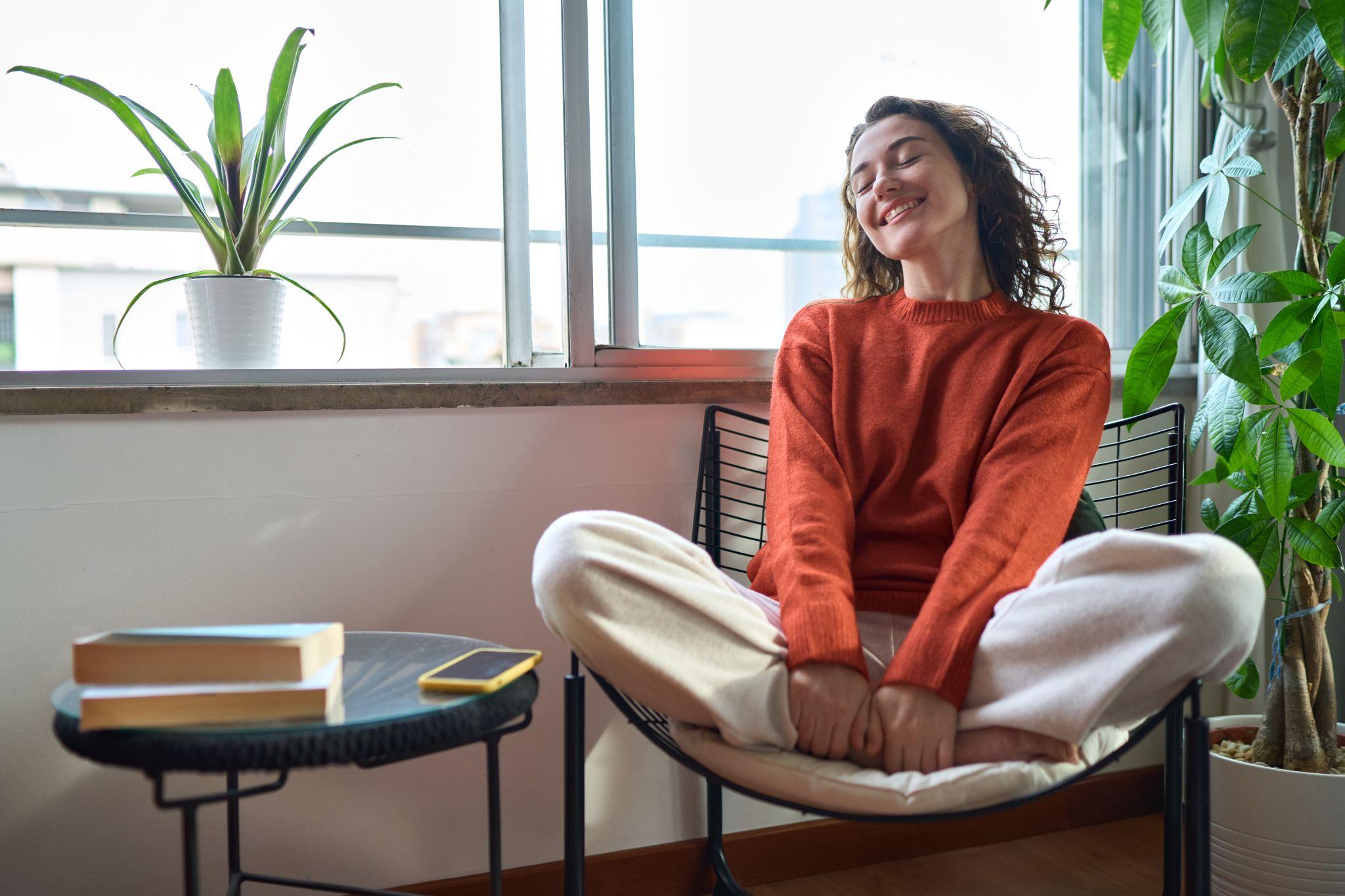 Young relaxed smiling pretty woman relaxing sitting on chair at home.