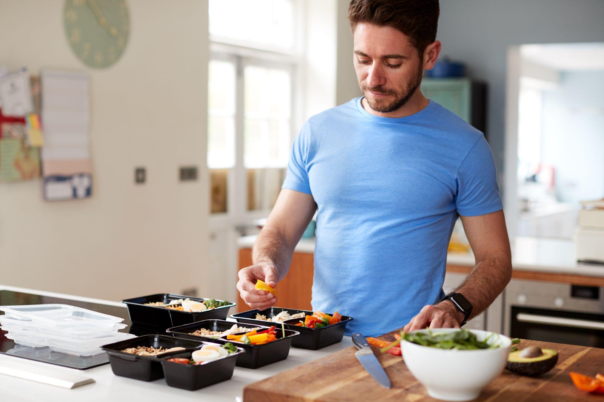 Man preparing batch of healthy meals at home in kitchen