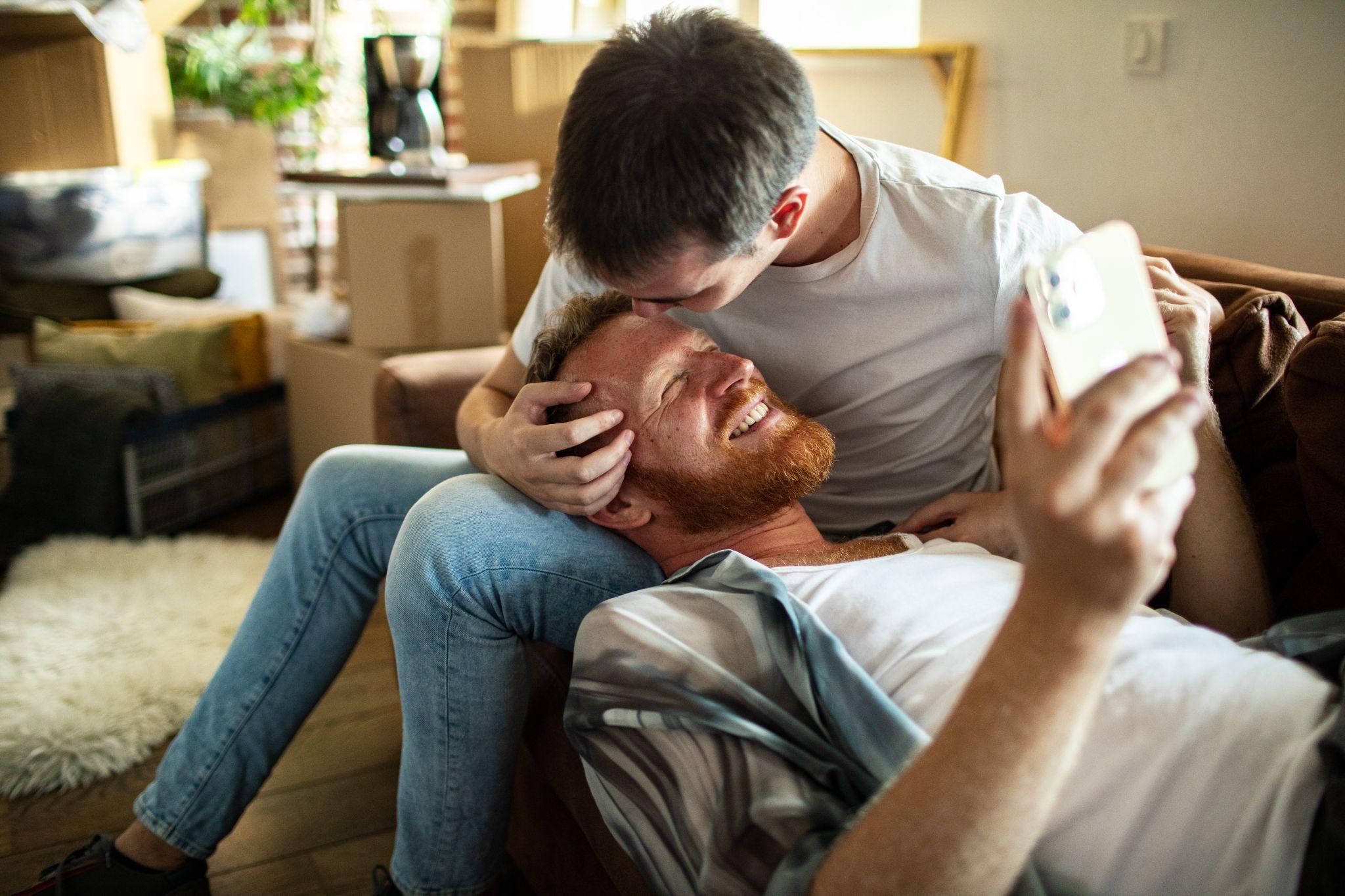 Tender moment between young gay couple in their living room