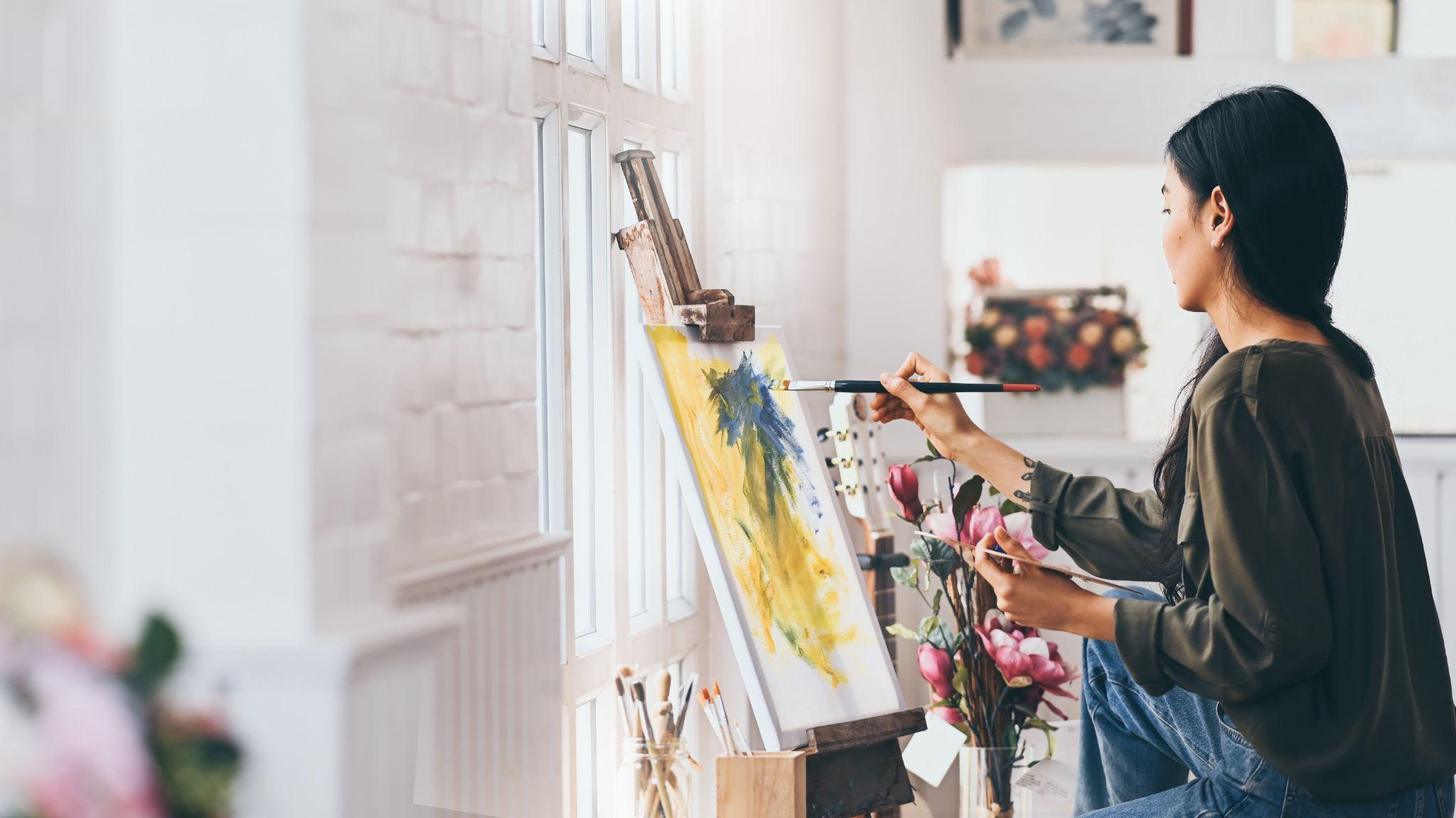 Woman artist works on abstract acrylic painting in the art studio.