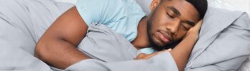 Young african-american man sleeping in bed at home