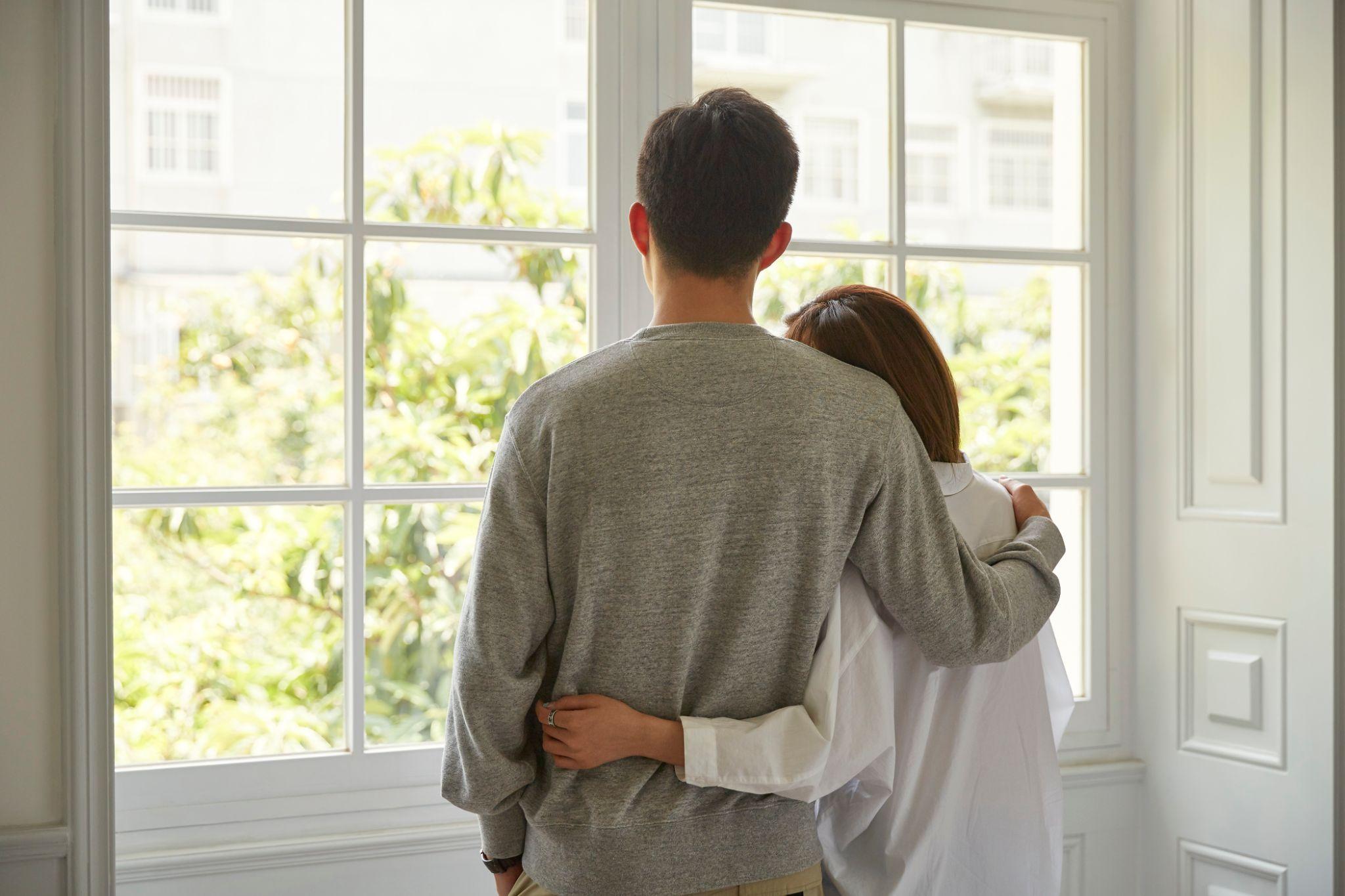 young asian couple looking out of window