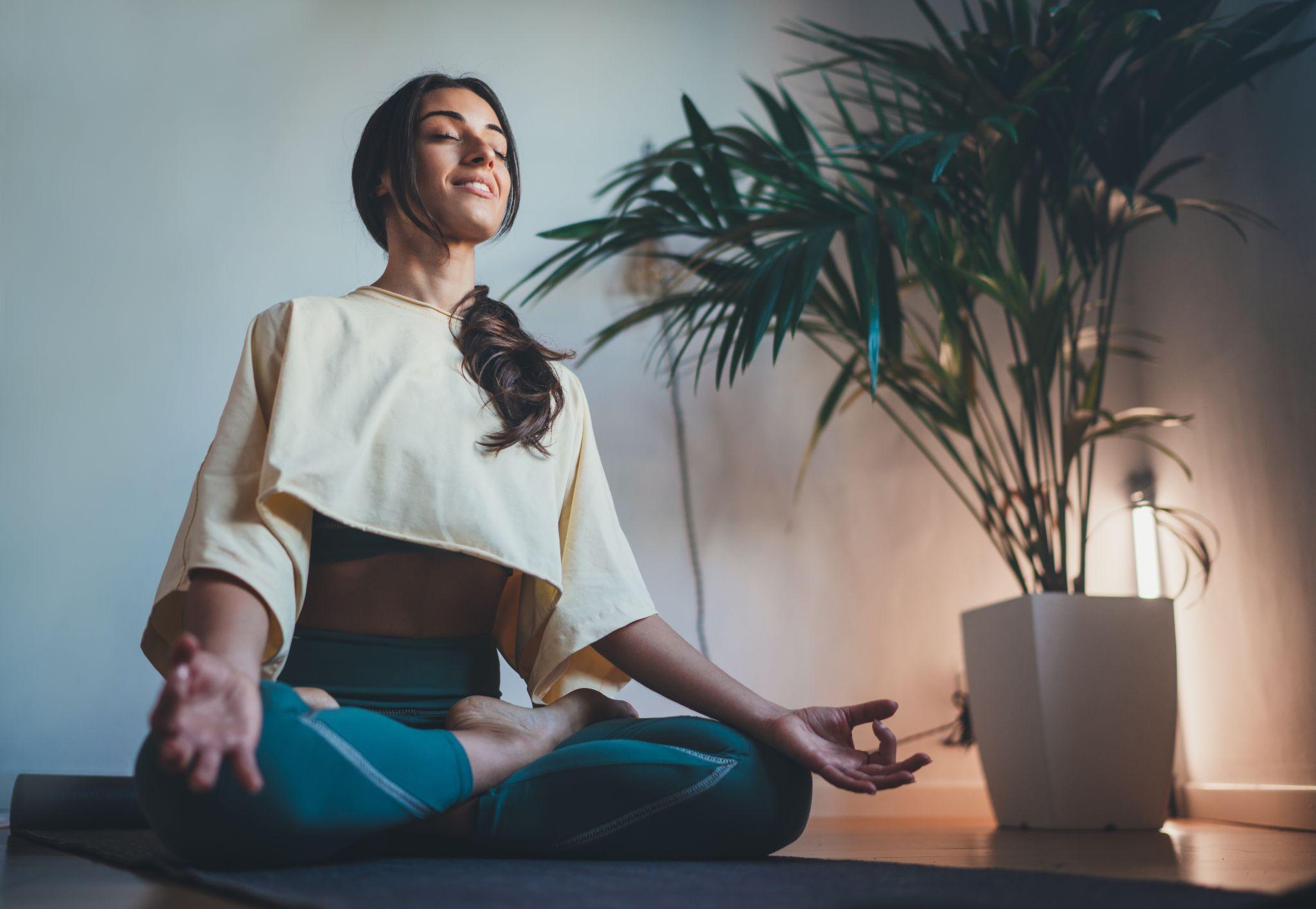 Young happy beautiful woman in cozy cropped sweatshirt and leggings practicing yoga at home