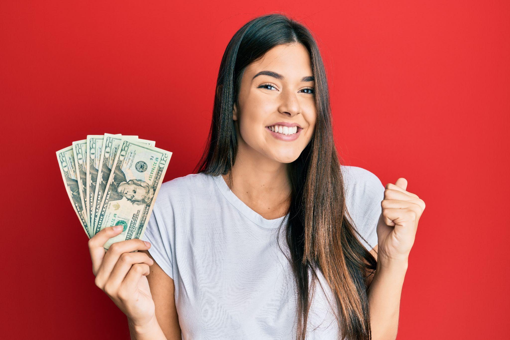 Young woman holding 20 dollars banknote screaming proud