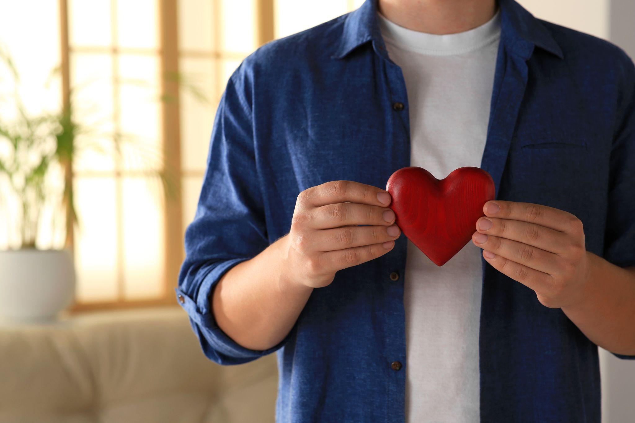 man holding red heart indoors