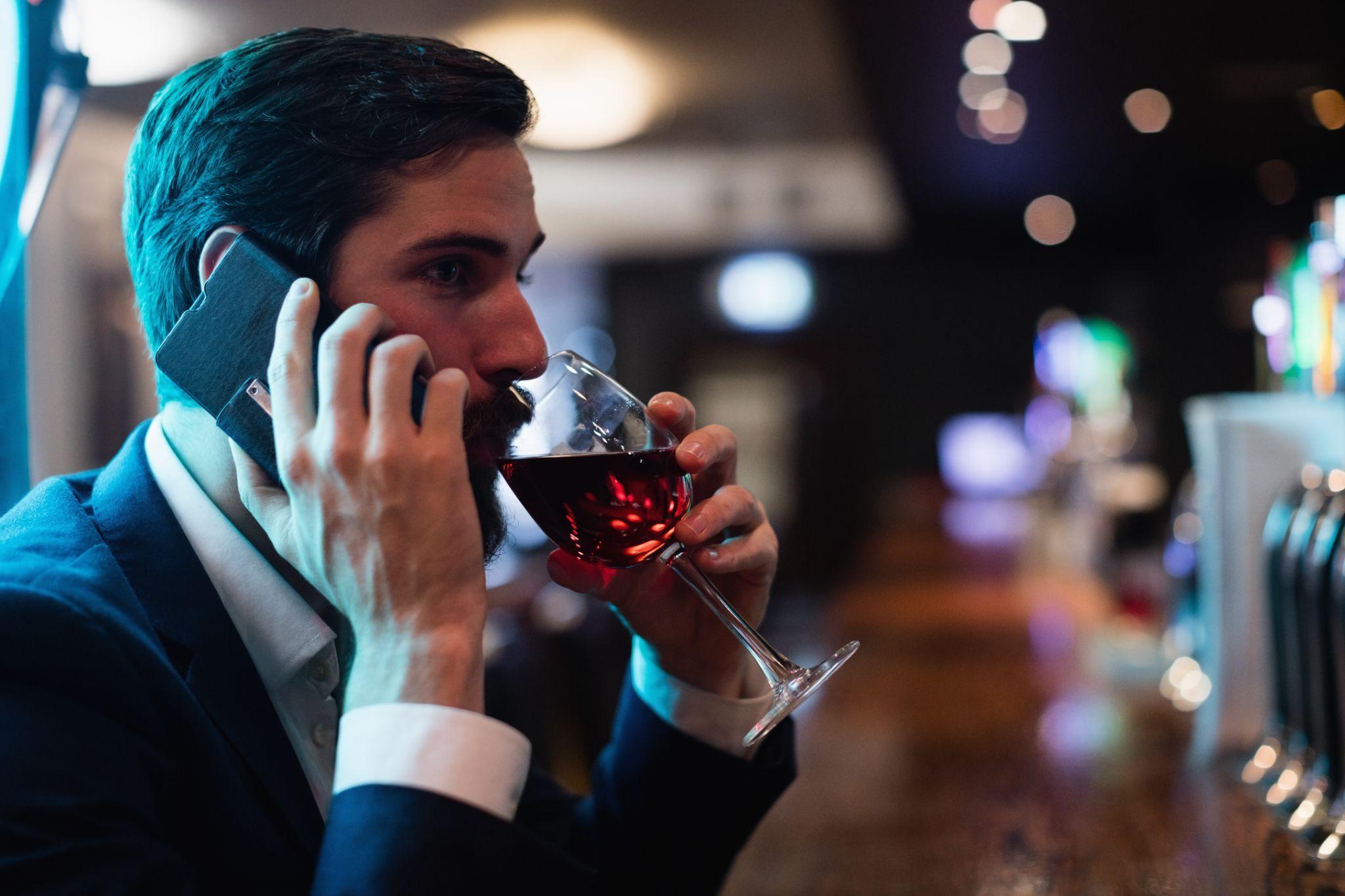 man sitting at bar counter holding whiskey glass