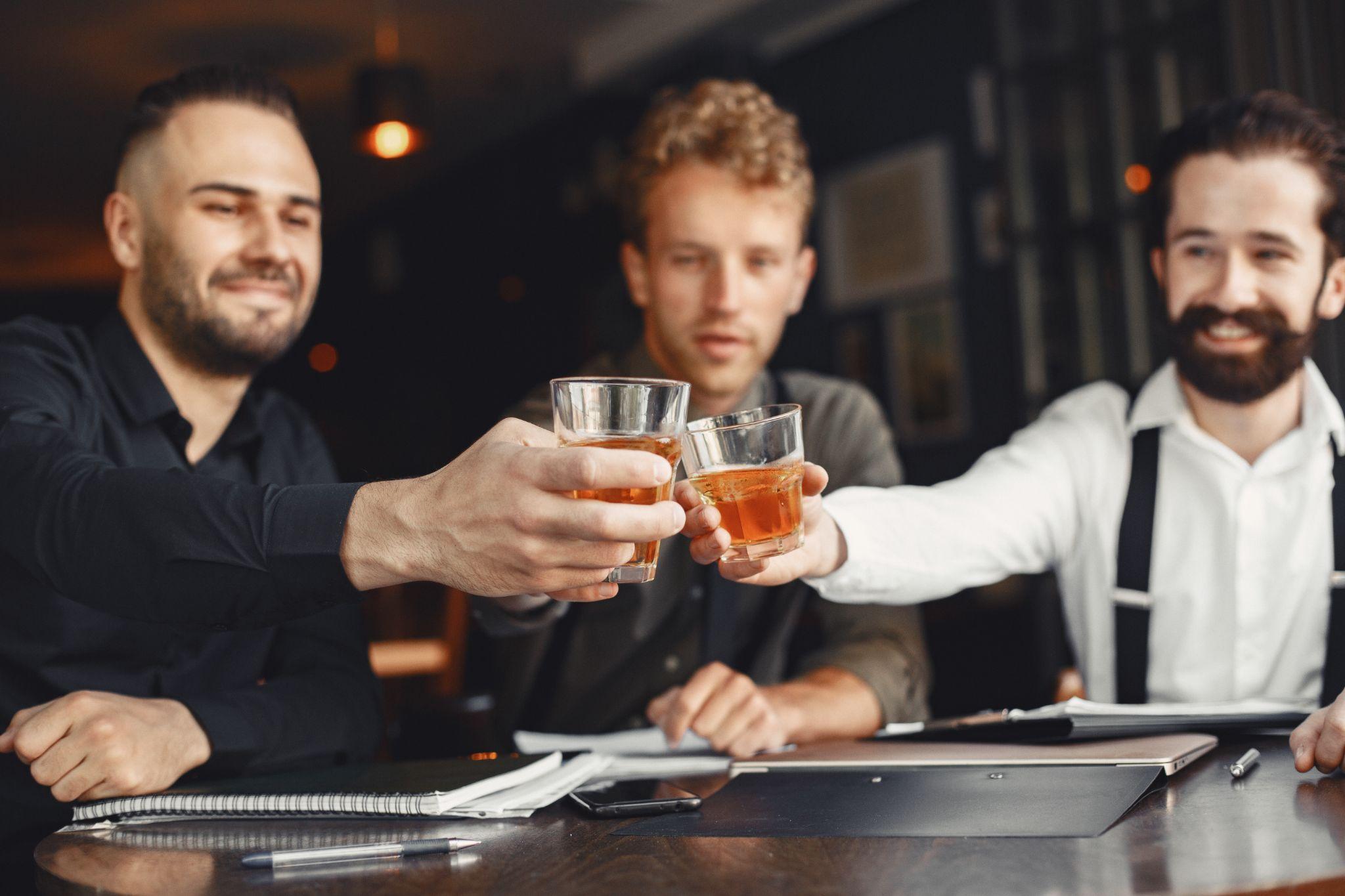 Three men are drinking whiskey and talking