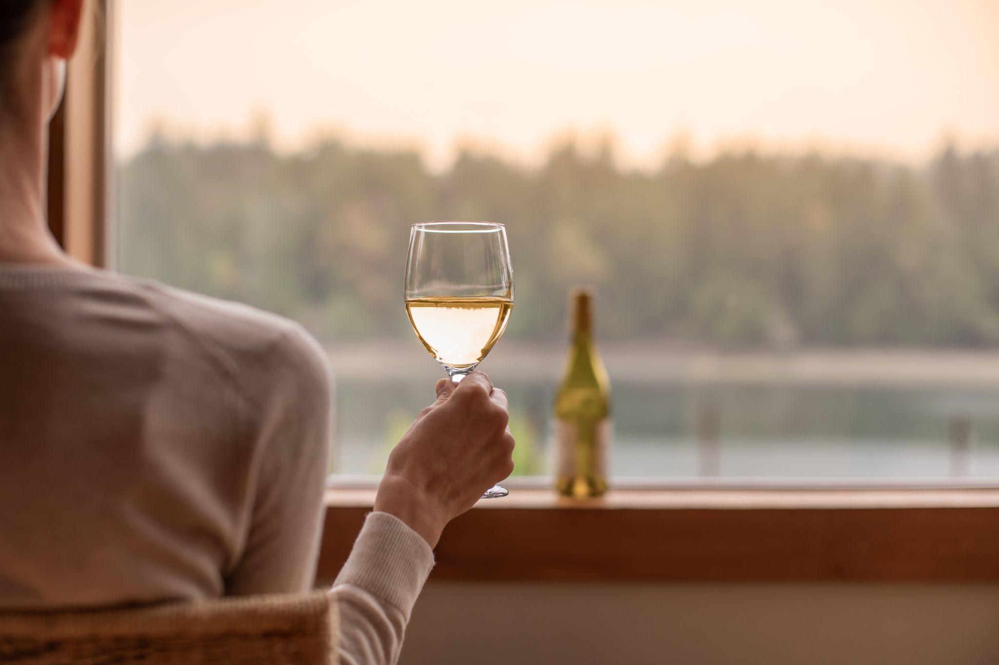 You woman enjoying glass of wine and a beautiful nature sunset lake view