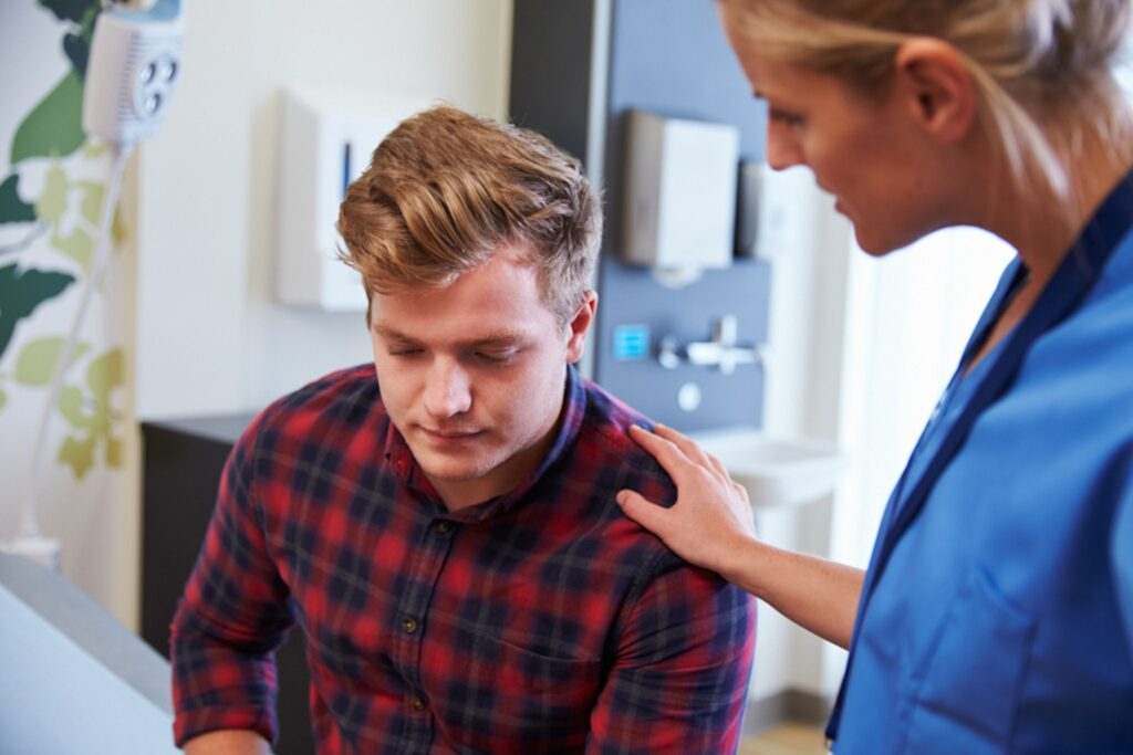 Nurse holding shoulder of young man after telling him results of drug test