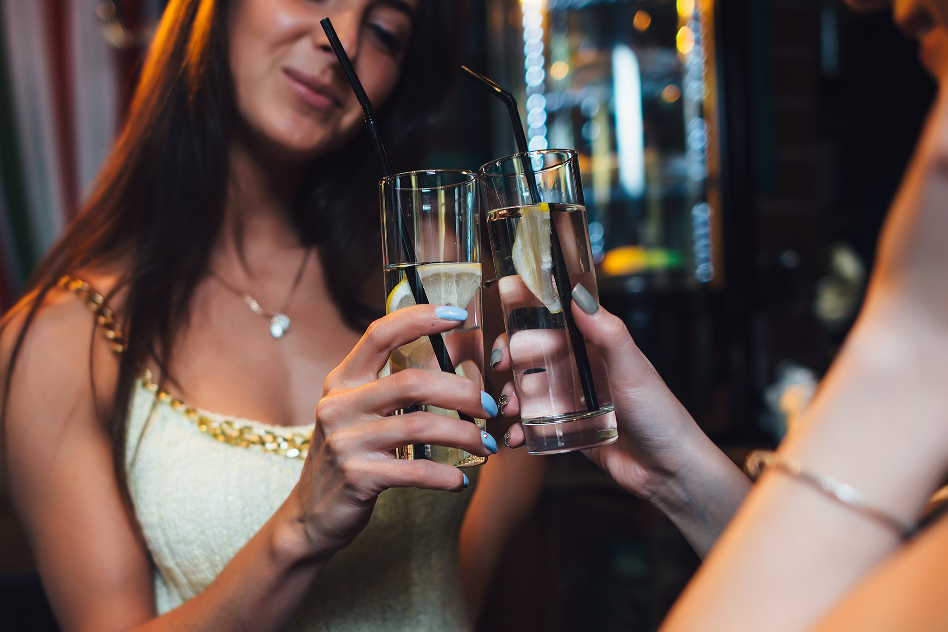 Two women drinking caffeine-free drinks in highball glasses