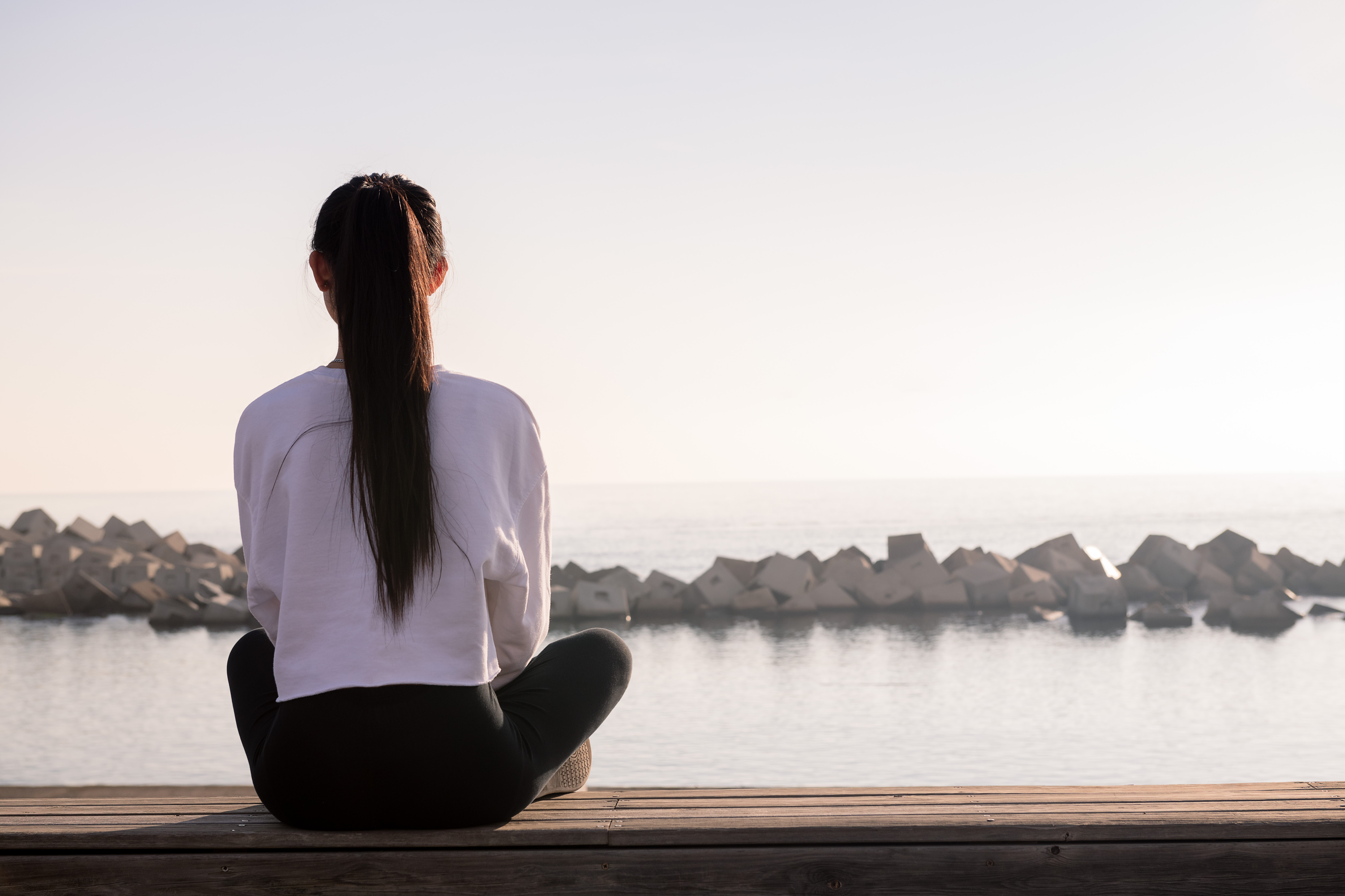 rear view of a young woman with long hair sitting meditating